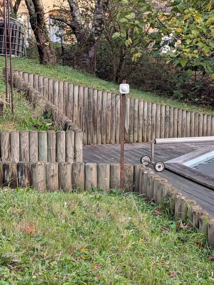 Détecteur de mouvement sur un piquet dans le jardin, près d'une bordure de rondins
