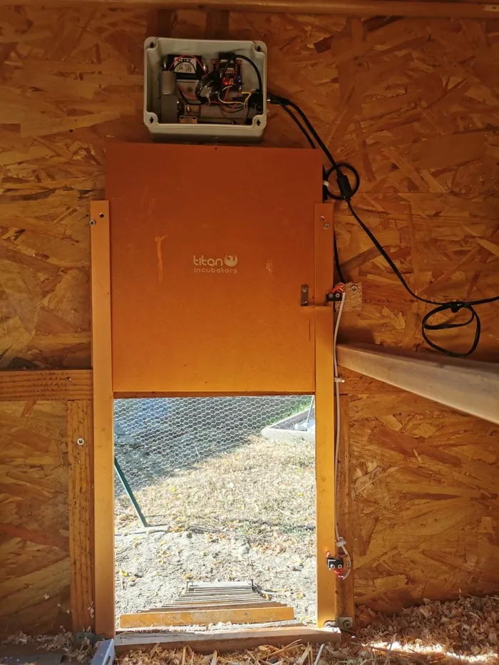 Porte guillotine motorisée à l'intérieur du poulailler, avec son boîtier de commande
