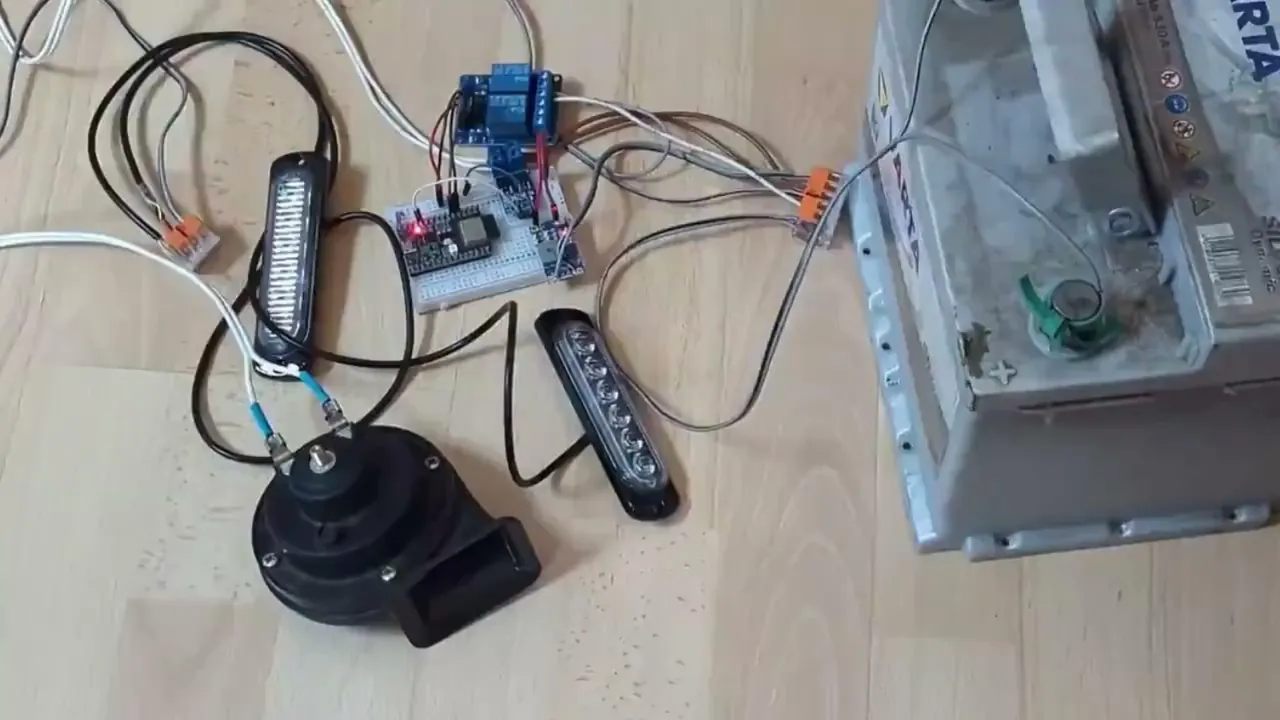 Montage sur le plancher : ESP32 et relais sur plaque d'essai, deux barres de LED stroboscopiques, un klaxon et une batterie de voiture